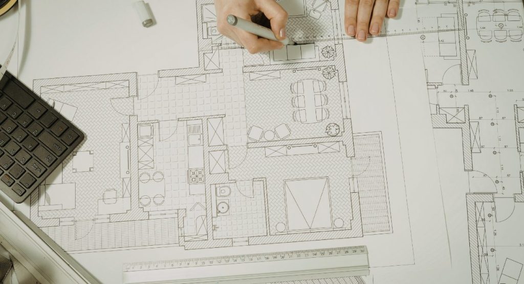 Mains d'architecte sur plans de construction illustrant le métier de BIM manager en bâtiment