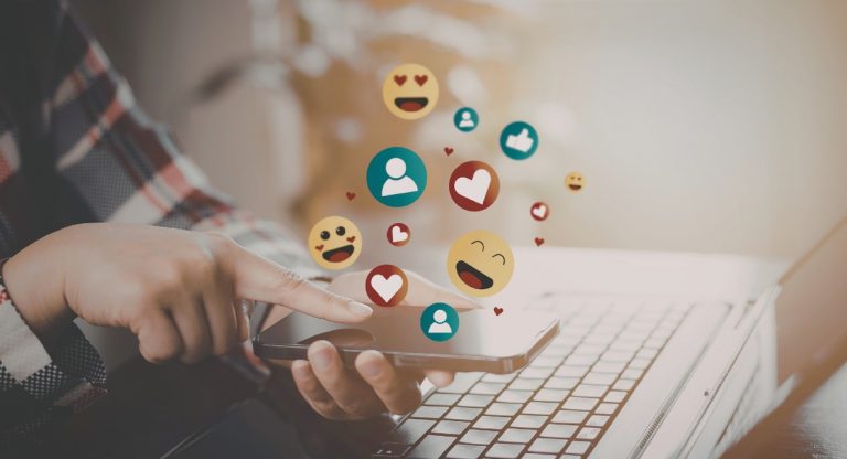 Mains tenant smartphone avec icônes like et emojis illustrant la planification calendrier social media