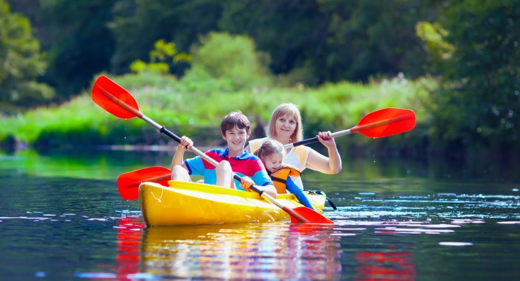 Famille pagayant en kayak jaune sur rivière illustrant les activités canoë et kayak sur la Lèche