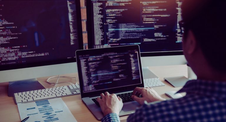 Développeur travaillant sur plusieurs écrans de code illustrant la construction d'un modèle conceptuel de données MCD