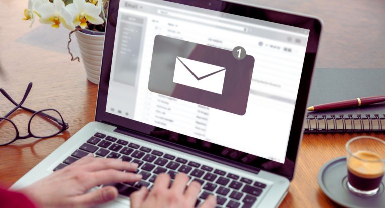 Mains sur laptop avec notification email pour prospection premier contact